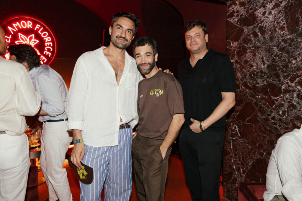 Tres hombres posando en un evento social con decoración elegante