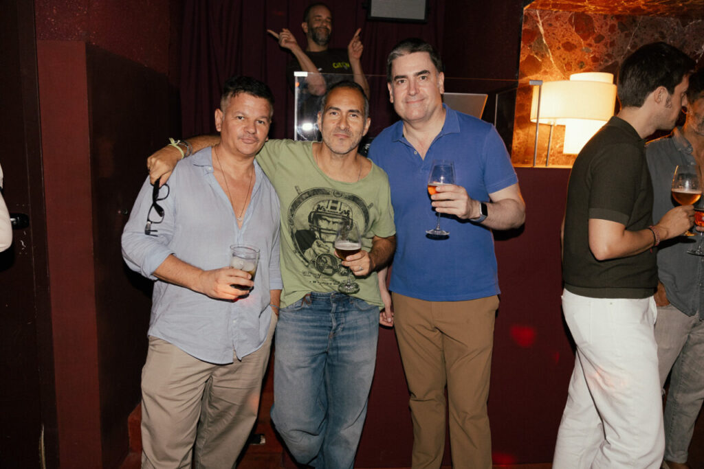 Tres hombres sosteniendo bebidas en un evento social