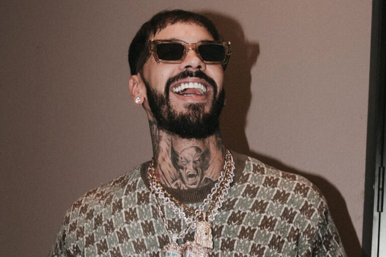 Revista Cultural y viajes desde Baleares 86 Anuel AA sonriendo con gafas de sol y joyas brillantes