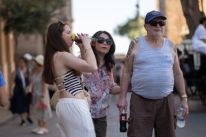 Turistas en la calle disfrutando de bebidas en un día caluroso