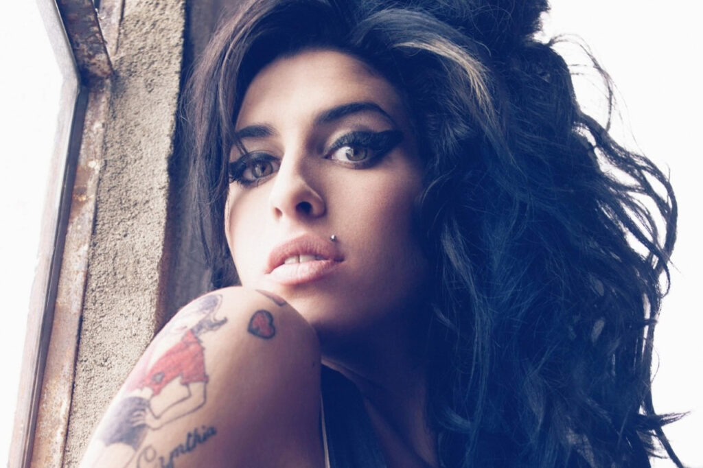 Retrato de Amy Winehouse con cabello rizado y tatuajes visibles