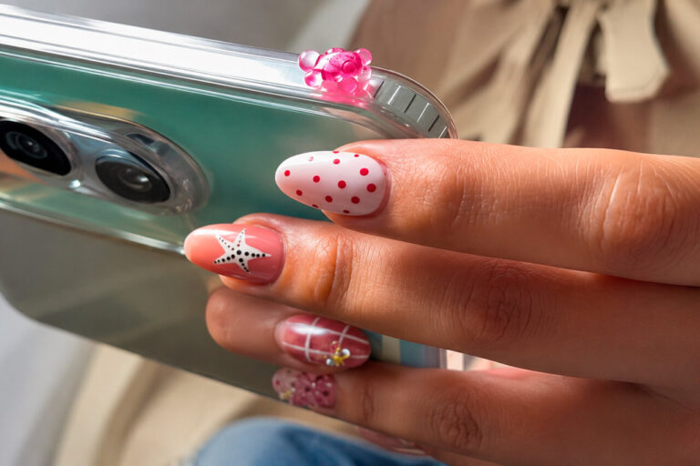 Mano sosteniendo un teléfono con tortugas adhesivas y manicura colorida